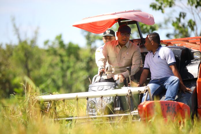 Wamentan Sudaryono saat mencoba Combine Harvester bersama petani di Ngawi. [astakom]