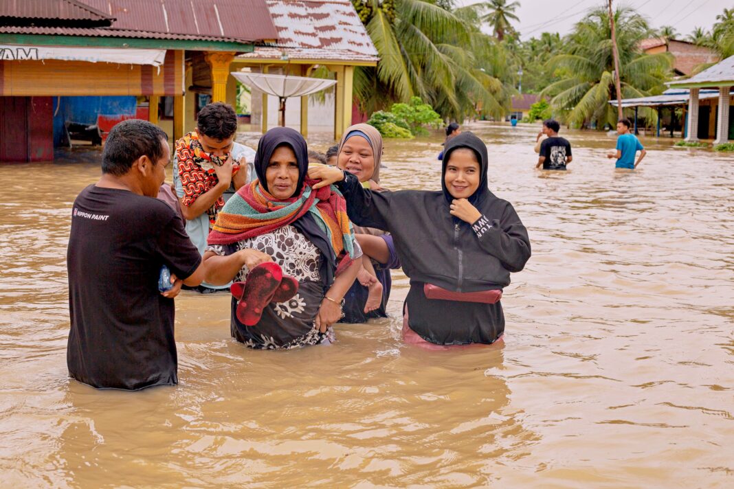 Warga melintasi banjir, di Nagari Kampung Galapuang Ulakan, Kecamatan Ulakan Tapakis, Kabupaten Padang Pariaman, Sumatera Barat, Senin (24/11).