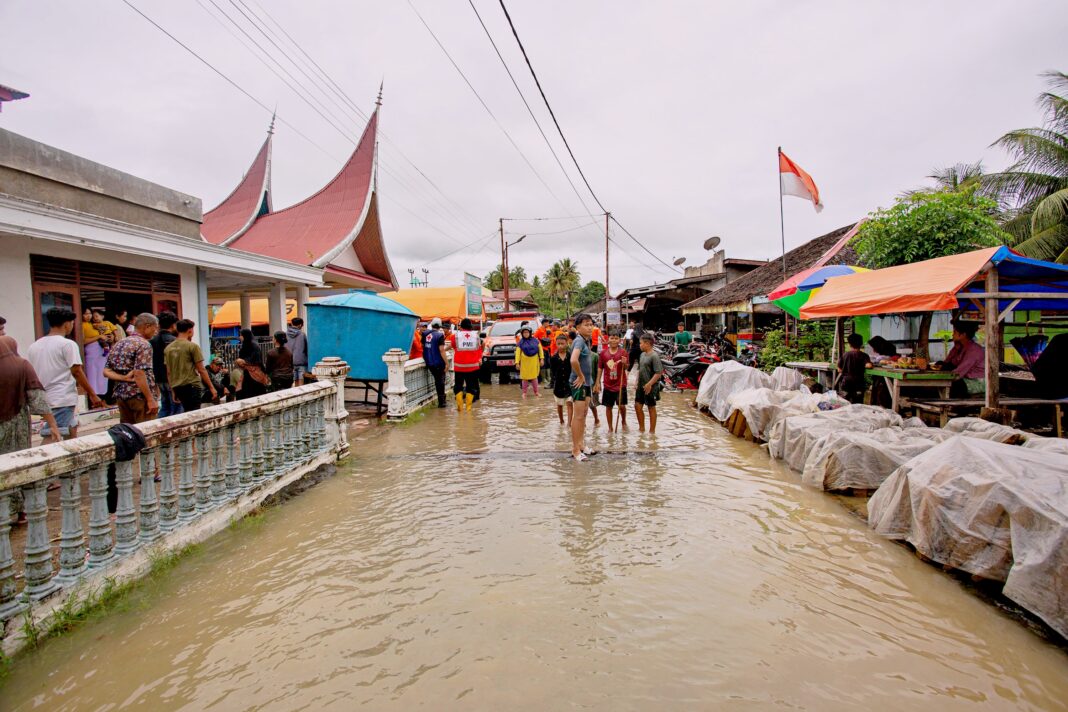 Warga melintasi banjir, di Nagari Kampung Galapuang Ulakan, Kecamatan Ulakan Tapakis, Kabupaten Padang Pariaman, Sumatera Barat, Senin (24/11).