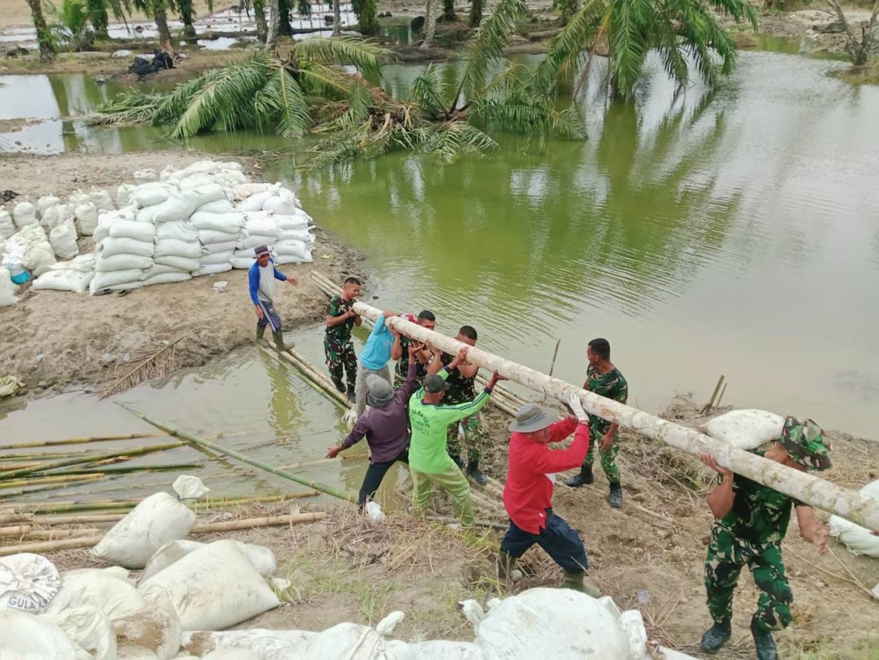 Koramil 07/Stabat dan Kodim 0203/Langkat bersama warga Desa Stabat Lama memperbaiki tanggul yang kembali jebol akibat hujan deras, di Kecamatan Wampu, Kabupaten Langkat, Sumatera Utara, Minggu (14/12).