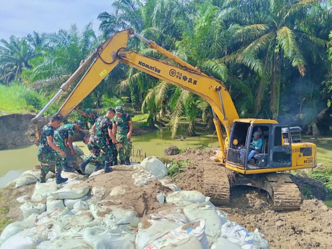 Koramil 07/Stabat dan Kodim 0203/Langkat bersama warga Desa Stabat Lama memperbaiki tanggul yang kembali jebol akibat hujan deras, di Kecamatan Wampu, Kabupaten Langkat, Sumatera Utara, Minggu (14/12).