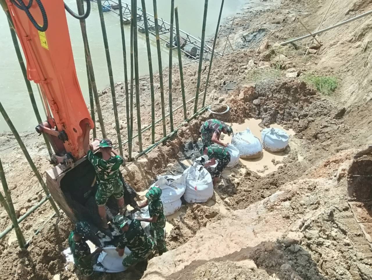 Koramil 07/Stabat dan Kodim 0203/Langkat bersama warga Desa Stabat Lama memperbaiki tanggul yang kembali jebol akibat hujan deras, di Kecamatan Wampu, Kabupaten Langkat, Sumatera Utara, Minggu (14/12).