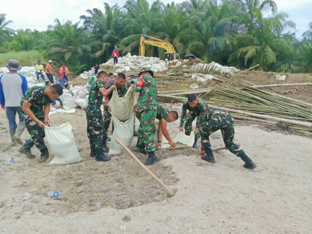 Koramil 07/Stabat dan Kodim 0203/Langkat bersama warga Desa Stabat Lama memperbaiki tanggul yang kembali jebol akibat hujan deras, di Kecamatan Wampu, Kabupaten Langkat, Sumatera Utara, Minggu (14/12).