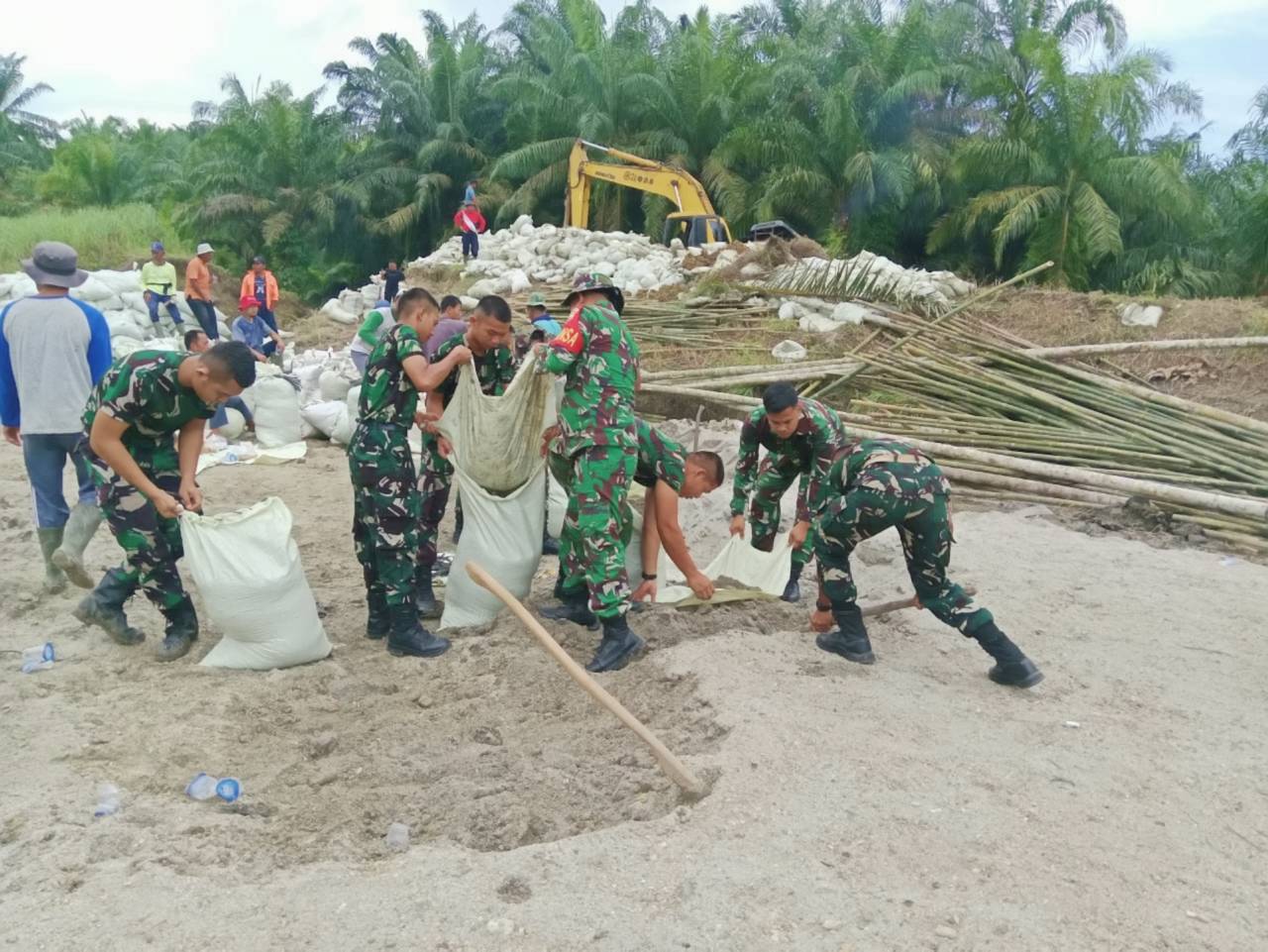 Koramil 07/Stabat dan Kodim 0203/Langkat bersama warga Desa Stabat Lama memperbaiki tanggul yang kembali jebol akibat hujan deras, di Kecamatan Wampu, Kabupaten Langkat, Sumatera Utara, Minggu (14/12).