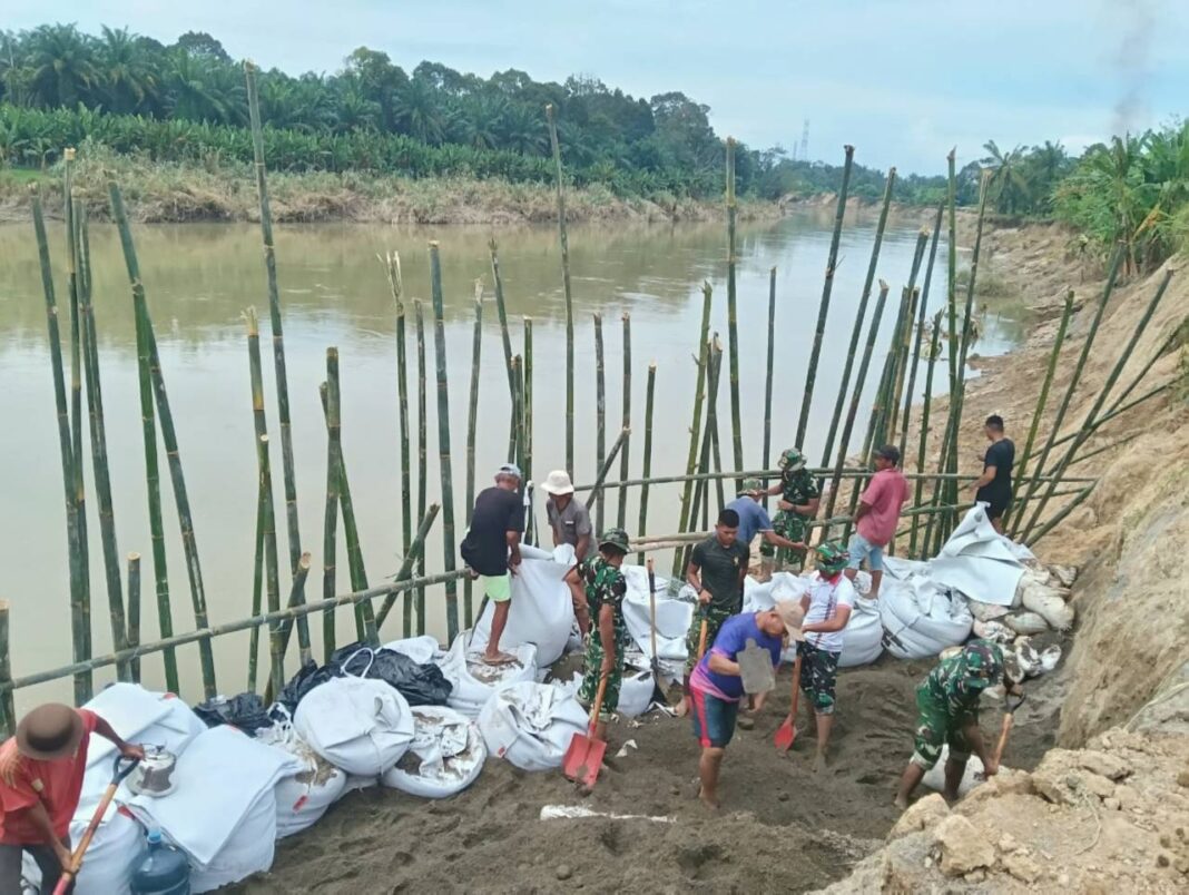 Koramil 07/Stabat dan Kodim 0203/Langkat bersama warga Desa Stabat Lama memperbaiki tanggul yang kembali jebol akibat hujan deras, di Kecamatan Wampu, Kabupaten Langkat, Sumatera Utara, Minggu (14/12).