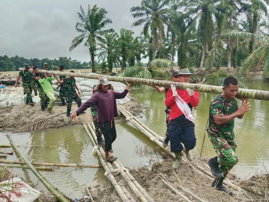Koramil 07/Stabat dan Kodim 0203/Langkat bersama warga Desa Stabat Lama memperbaiki tanggul yang kembali jebol akibat hujan deras, di Kecamatan Wampu, Kabupaten Langkat, Sumatera Utara, Minggu (14/12).
