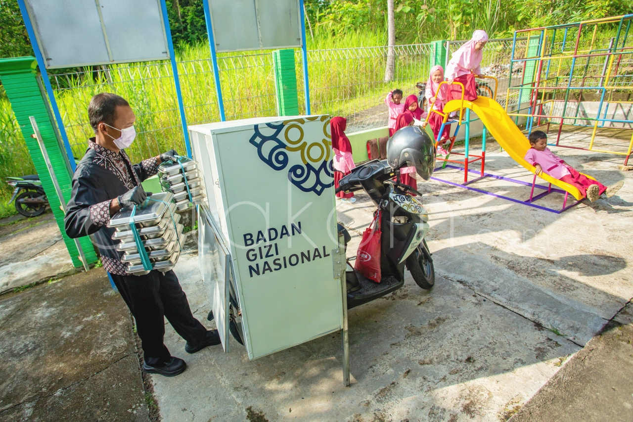 Satuan Pelayanan Pemenuhan Gizi (SPPG) Pengasih 1 mengendarai sepeda motor distribusi Makanan Bergizi Gratis (MBG) ke sekolah-sekolah, di Kulon Progo, Daerah Istimewa (DI) Yogyakarta, Senin (1/12).