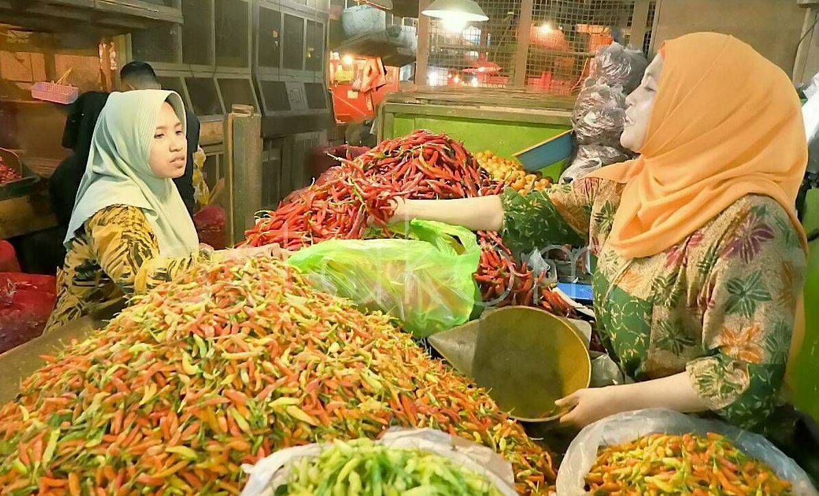 Pedagang menunjukkan stok bawang dan cabai rawit di Pasar Pabean Surabaya
