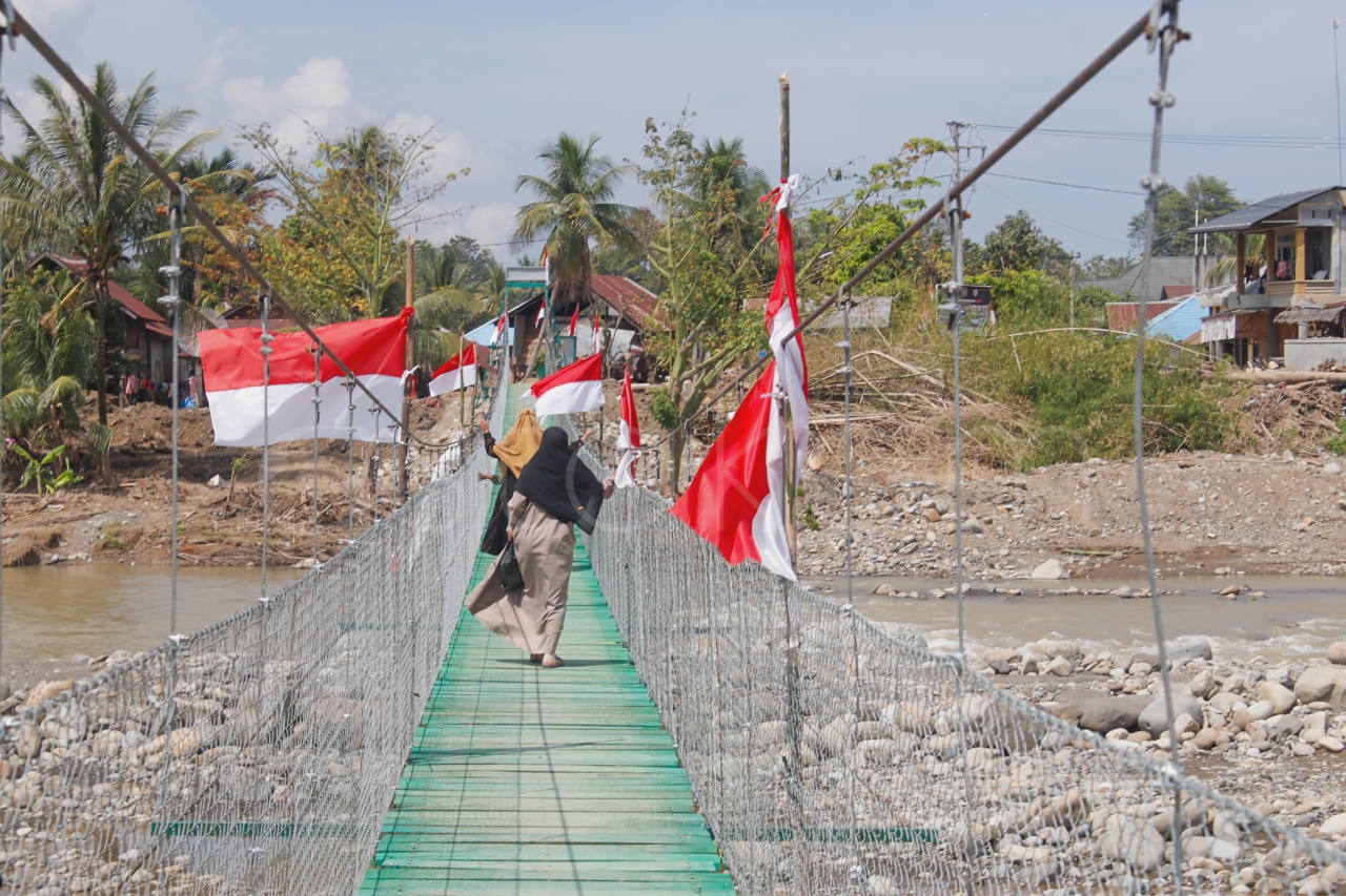 Warga melintasi Jembatan Gantung Garuda pasca banjir Pidie Jaya.