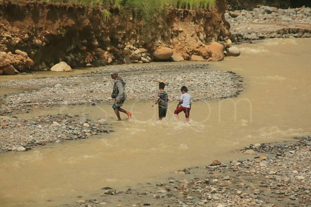 Warga Kelurahan Lambung Bukit menyeberangi sungai Batu Busuk Padang.
