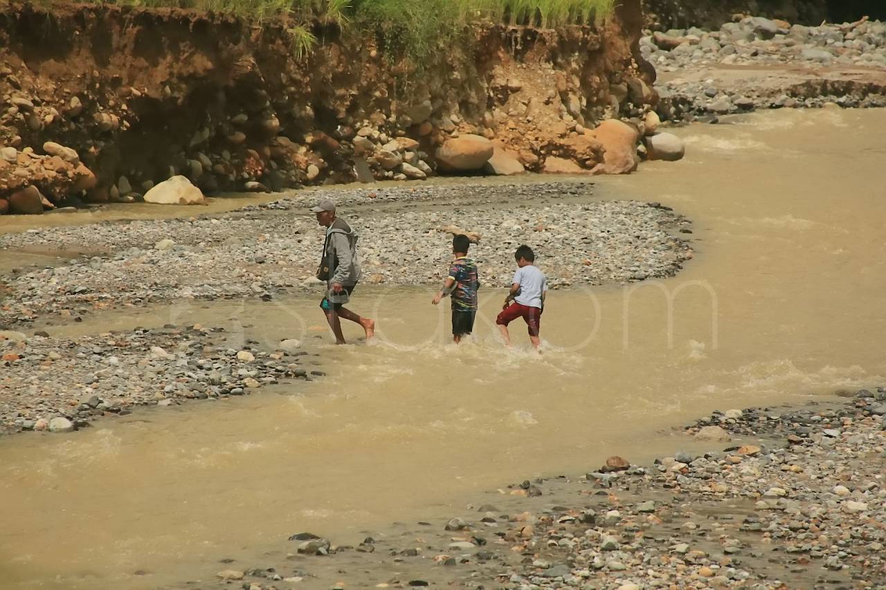 Warga Kelurahan Lambung Bukit menyeberangi sungai Batu Busuk Padang.