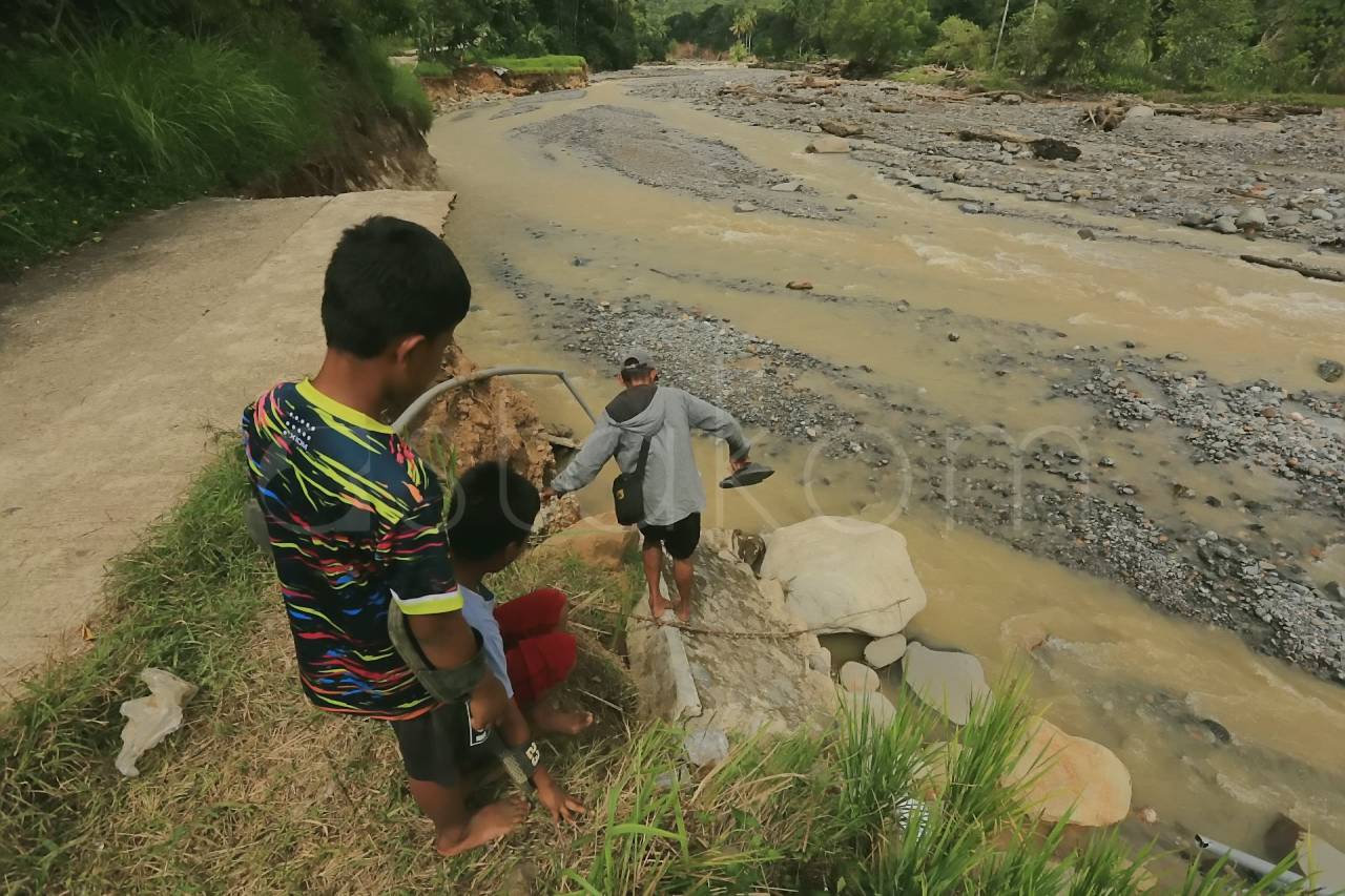 Warga Kelurahan Lambung Bukit menyeberangi sungai Batu Busuk Padang.