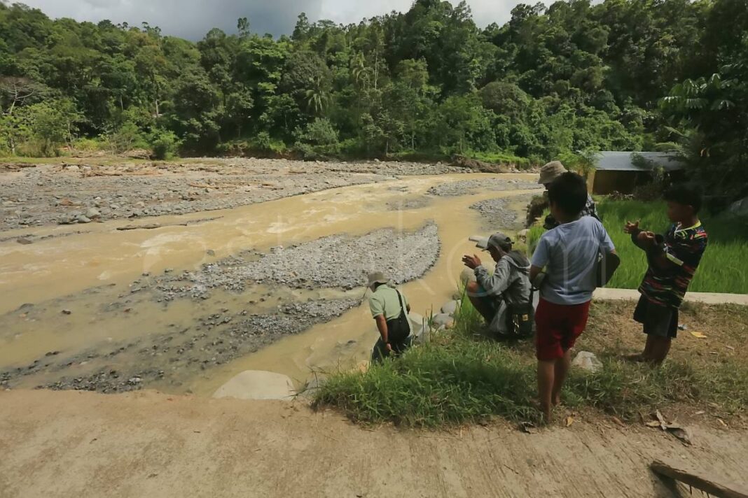 Warga Kelurahan Lambung Bukit menyeberangi sungai Batu Busuk Padang.